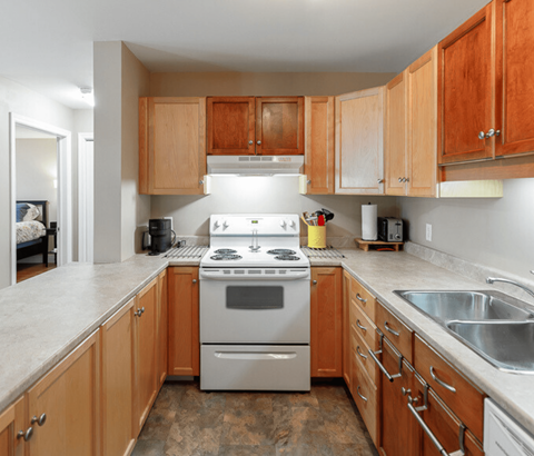 A kitchen with a stove top oven and wooden cabinets.