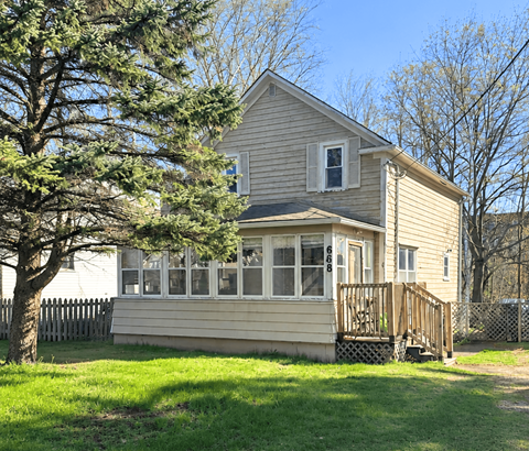 A house with a deck and a tree in front.