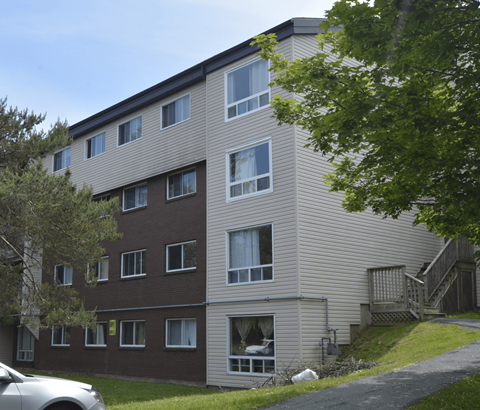 A large apartment building with a car parked in front.