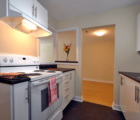 A kitchen with a white stove and white cabinets.