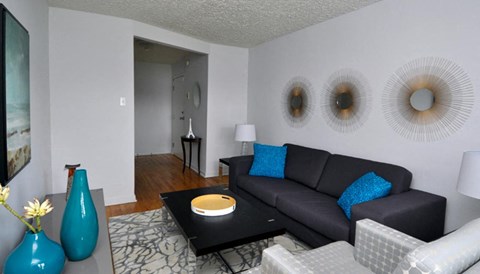 A living room with a black couch and blue vases.