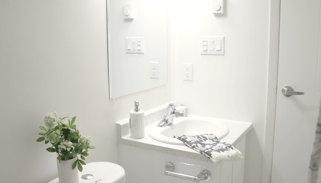 A white sink with a towel and a plant on the toilet.