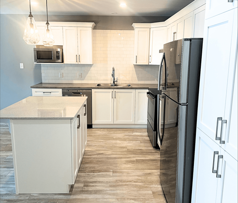 A kitchen with a black refrigerator and white cabinets.