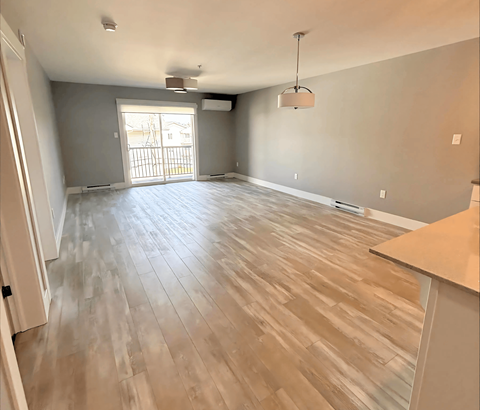 A room with wooden flooring and a large window.
