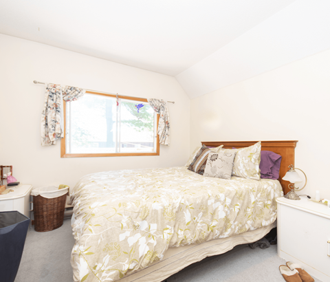 A bedroom with a large bed and a window with curtains.