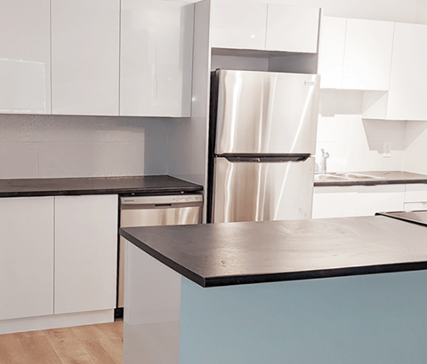 A kitchen with a stainless steel refrigerator and white cabinets.