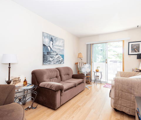 A living room with a brown couch and a painting on the wall.