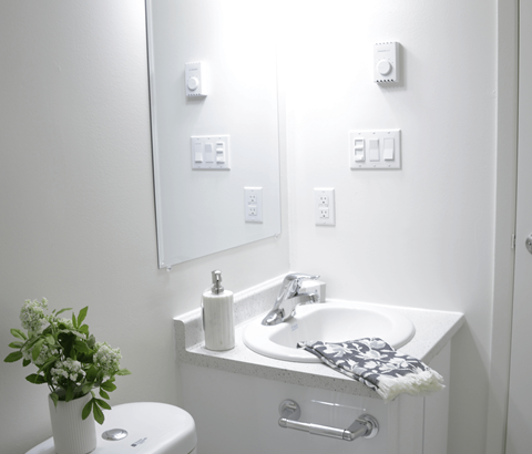 A white bathroom with a toilet, sink, and mirror.