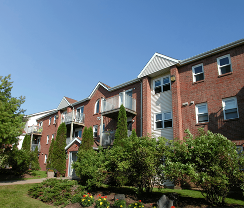 A red brick apartment building with a green lawn in front.