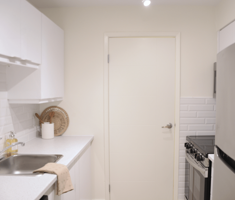 A white kitchen with a sink and a door.