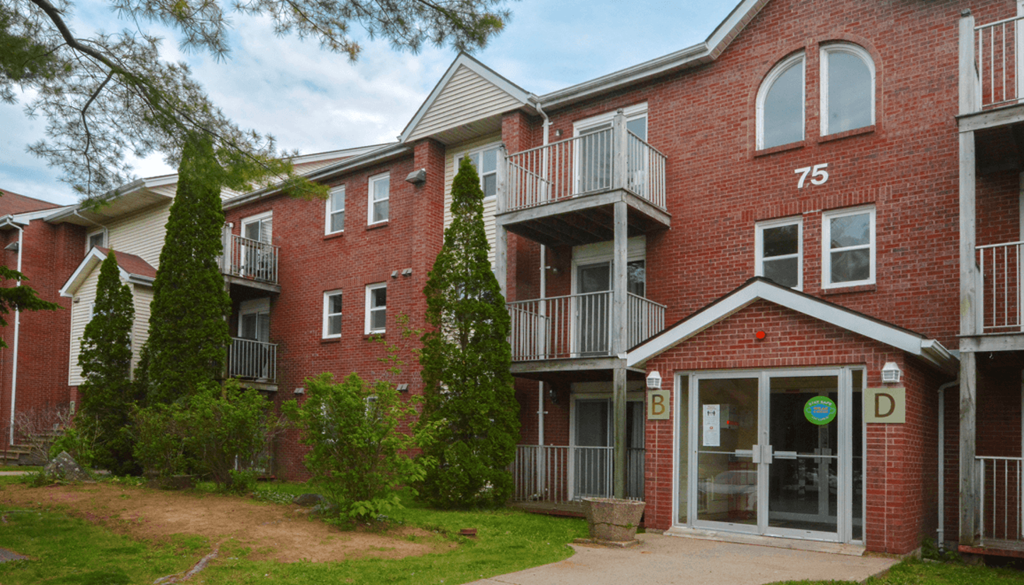 a red brick apartment building with two balconies and a sidewalk