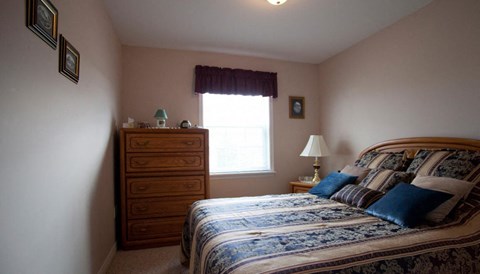 A bedroom with a bed, nightstand, and window.