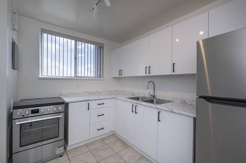 A kitchen with white cabinets and a stainless steel refrigerator.