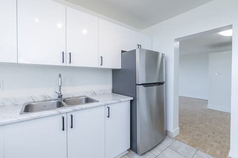 A kitchen with white cabinets and a stainless steel refrigerator.