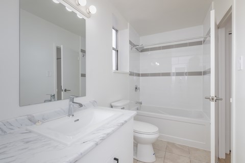 A white bathroom with a toilet, sink, and bathtub.