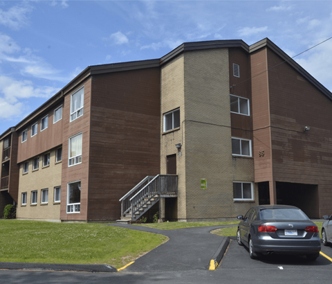 A car is parked in a parking lot in front of a brown building.