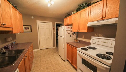 A kitchen with a stove, sink, and refrigerator.