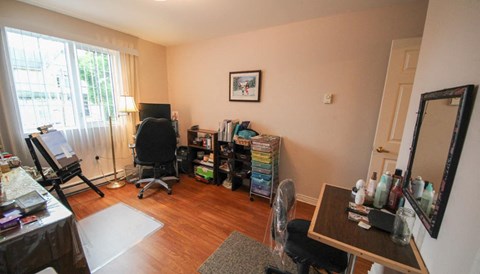 A room with a desk, chair, and a fan.