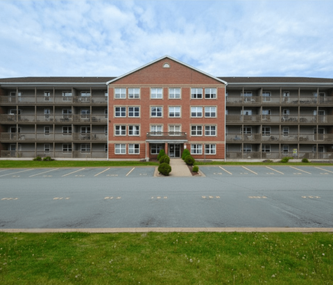 A red brick building with a parking lot in front.