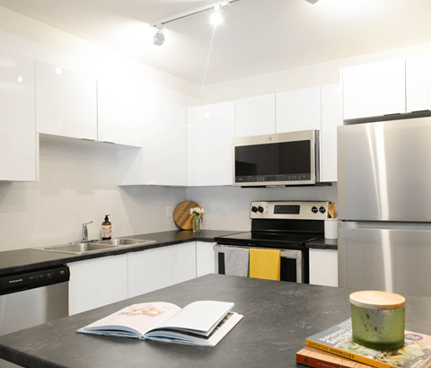 A modern kitchen with a black countertop and stainless steel appliances.