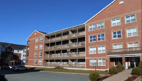 A large red brick building with a parking lot in front.