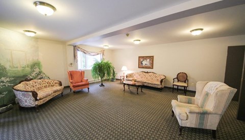 A living room with a sofa, chair, and two beds.