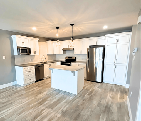 A kitchen with white cabinets and a wooden floor.