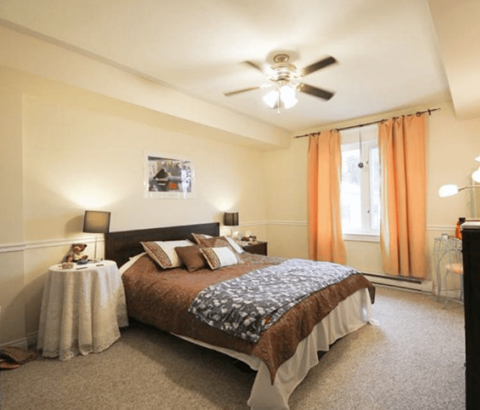 A bedroom with a large bed and a ceiling fan.