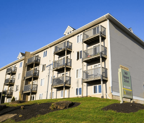 A multi-story apartment building with a sign that reads "Sale" in front of it.