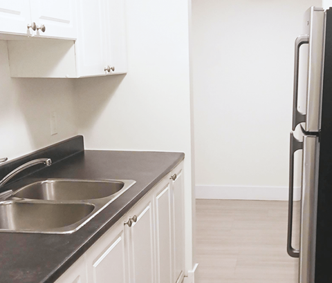 A kitchen with a black countertop and a stainless steel sink.