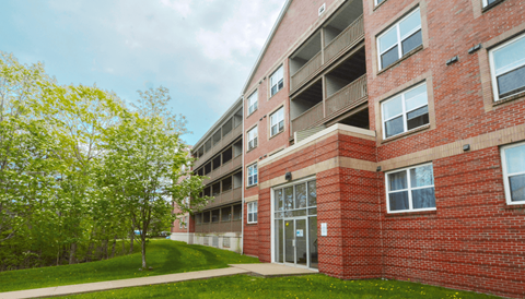 A red brick building with a green lawn in front.