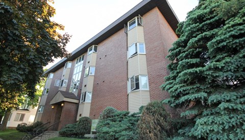 A red brick building with a tree in front.