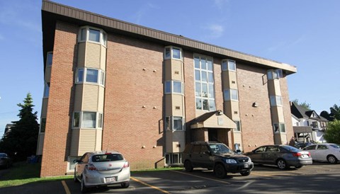 A parking lot with cars and a building with a brown and beige facade.