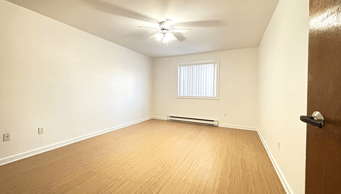 A room with a ceiling fan and a window with blinds.