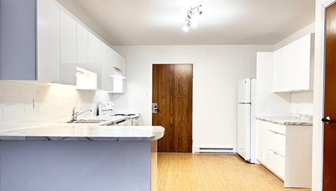 A kitchen with a sink, counter, and refrigerator.