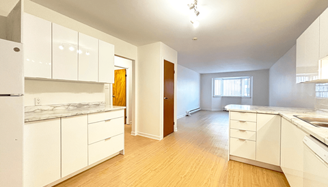 A kitchen with white cabinets and a wooden floor.