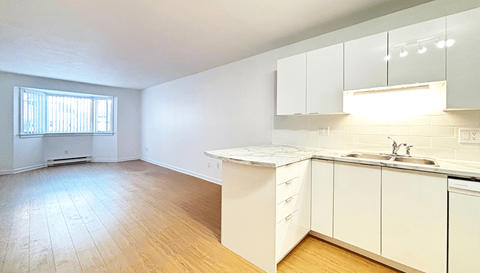 A kitchen with white cabinets and a wooden floor.