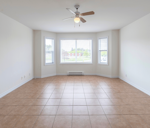 Empty room with a ceiling fan and tiled floor.