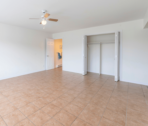A room with a ceiling fan and tile flooring.