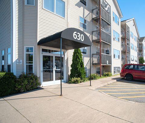 A building with the number 630 on it has a red car parked in front of it.