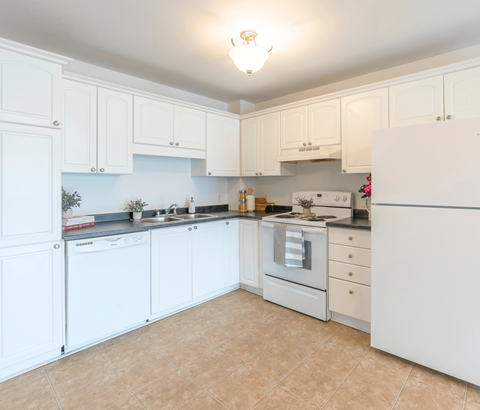 A kitchen with white cabinets and appliances.