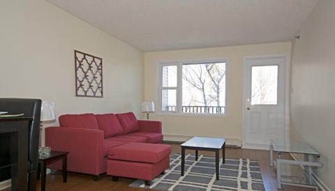 A red couch sits in a living room with a wooden coffee table in front of it.