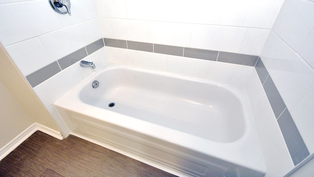 a white bath tub in a white tiled bathroom