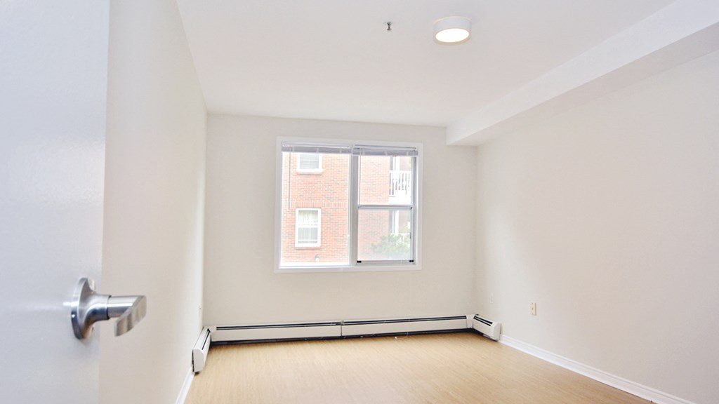 an empty living room with a window and wood flooring
