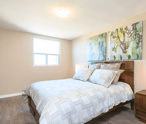 A bedroom with a large bed and two paintings on the wall.