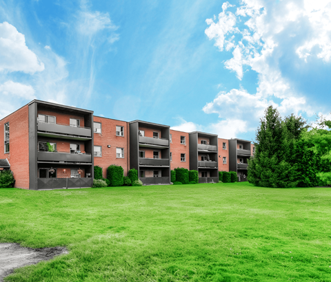 A row of red brick apartment buildings with green grass in front.
