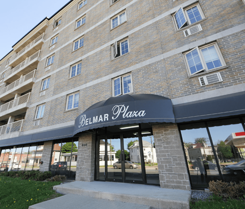The Belmar Plaza building is a multi-story brick structure with a black awning.