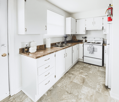 A kitchen with white cabinets and a white stove.