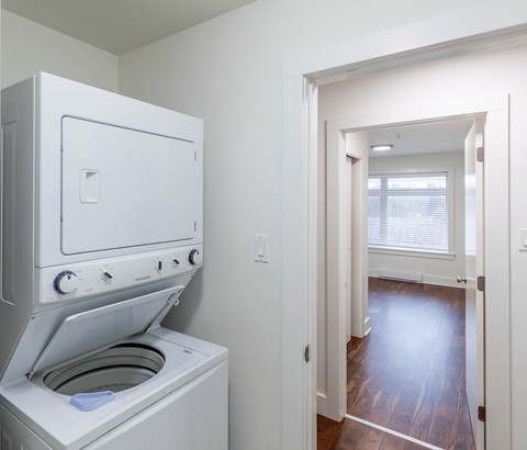 A white oven with a door open is in a room with a wooden floor.