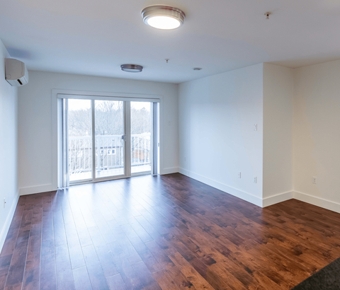 A room with a sliding glass door and wood flooring.
